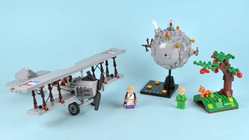 an old fashioned toy airplane is sitting next to two lego figures