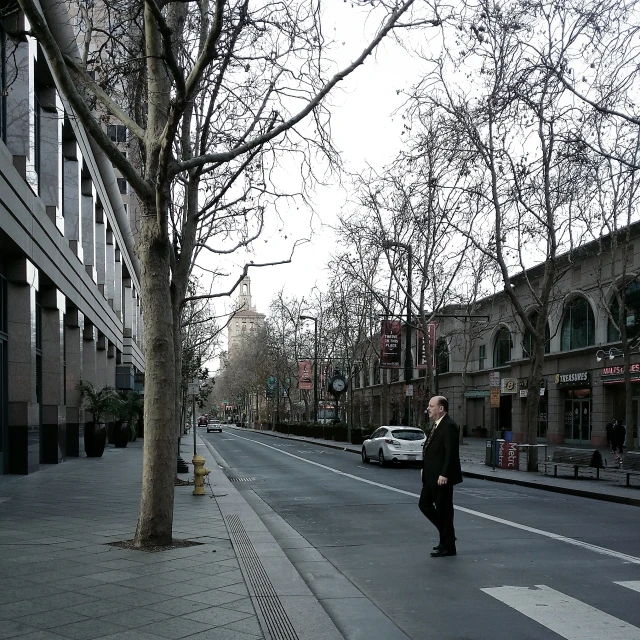 a man walking down the street past tall buildings