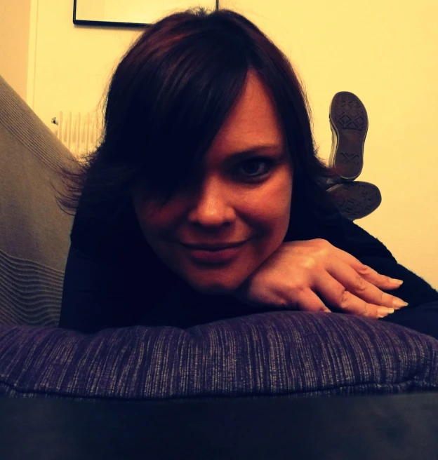 woman with big smile looking at camera from behind couch