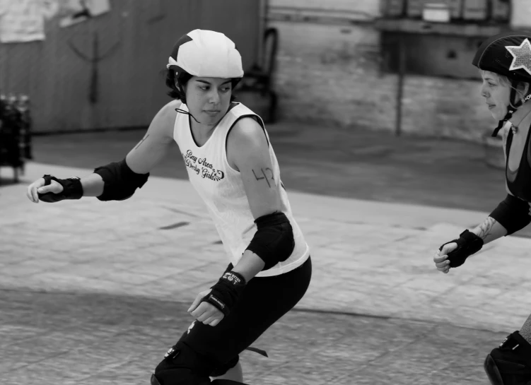 two men skate boarding down a street while wearing helmets