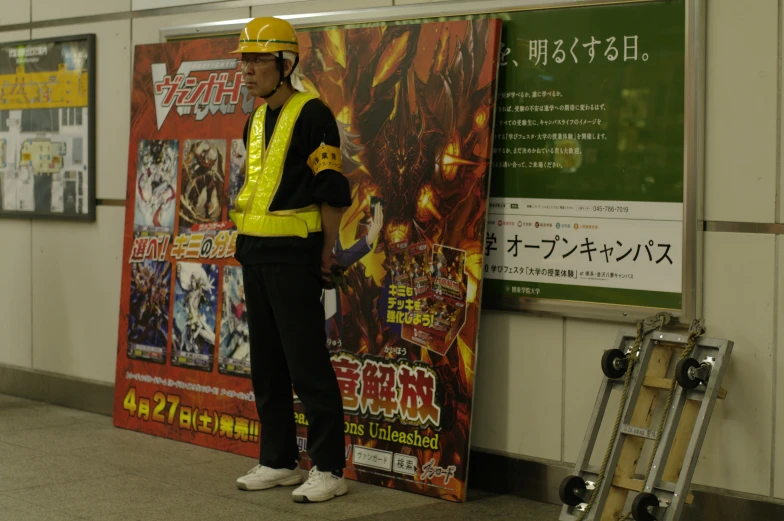 man in yellow safety vest standing by a poster