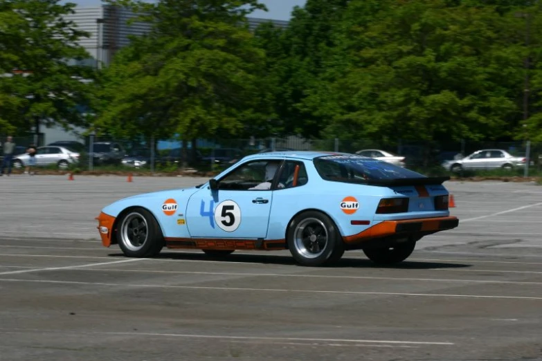 a race car in a parking lot with trees around it