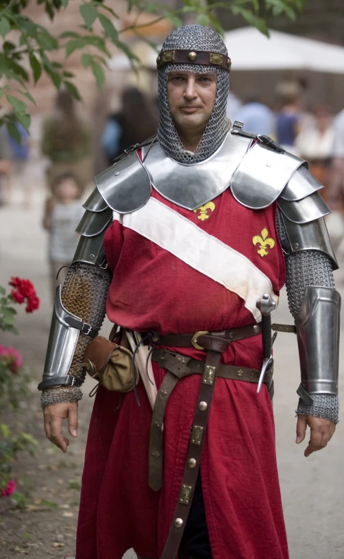 a man dressed in armor and carrying a sword on a path