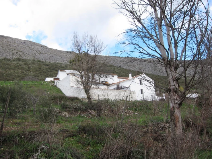 a small house sitting on top of a hill surrounded by green hills