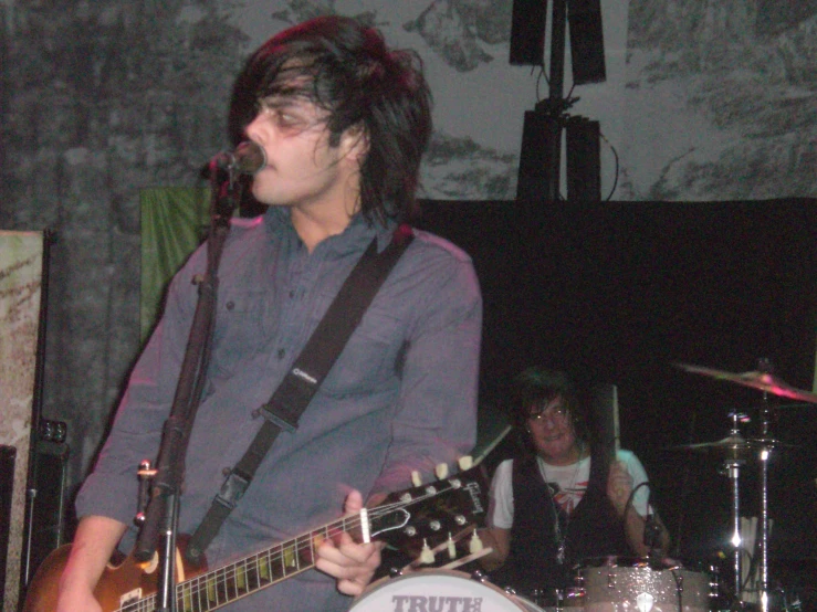 a man playing guitar with other musicians in background