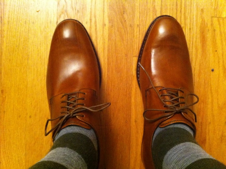 the man's legs wearing striped socks and brown leather shoes