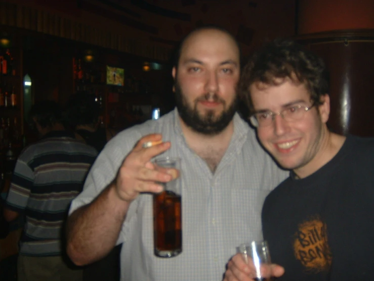 two males standing together while holding drinks