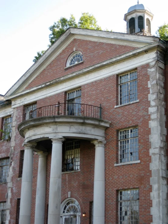 a red brick building with lots of columns and a clock on it's side