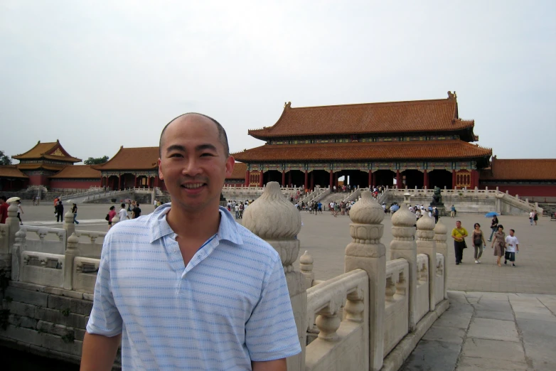 a man standing in front of a chinese building with red roof