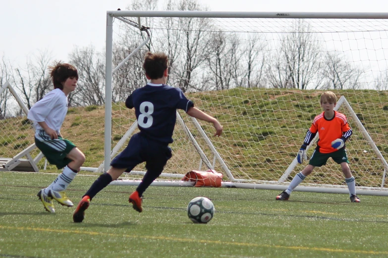 a  in green kicking at a soccer ball