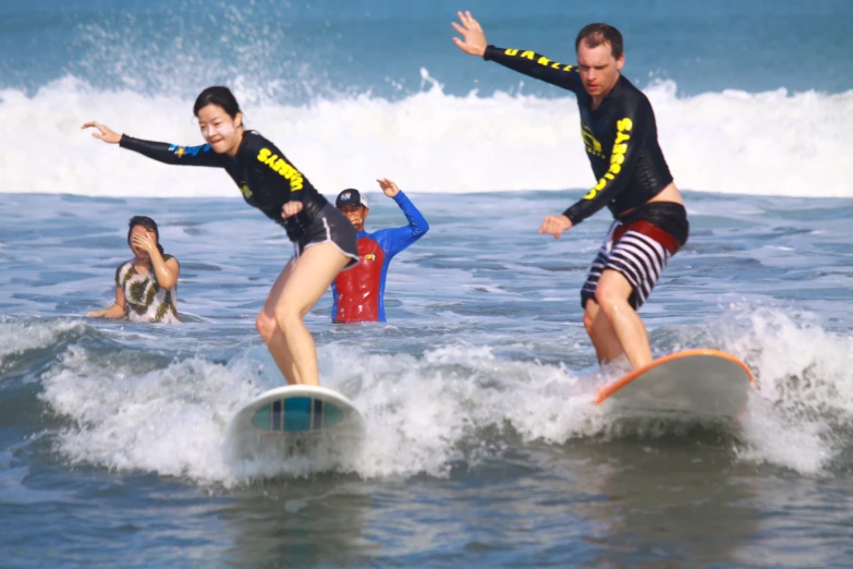 three people in wet suits riding surf boards
