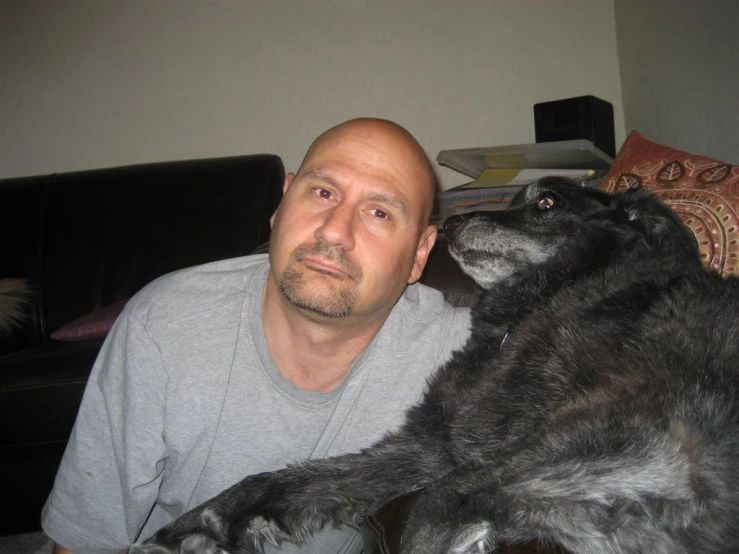 a man holding a large black dog on top of a couch