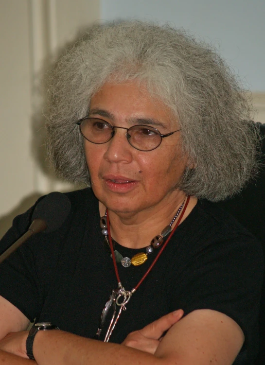 a person with white hair and glasses, sitting