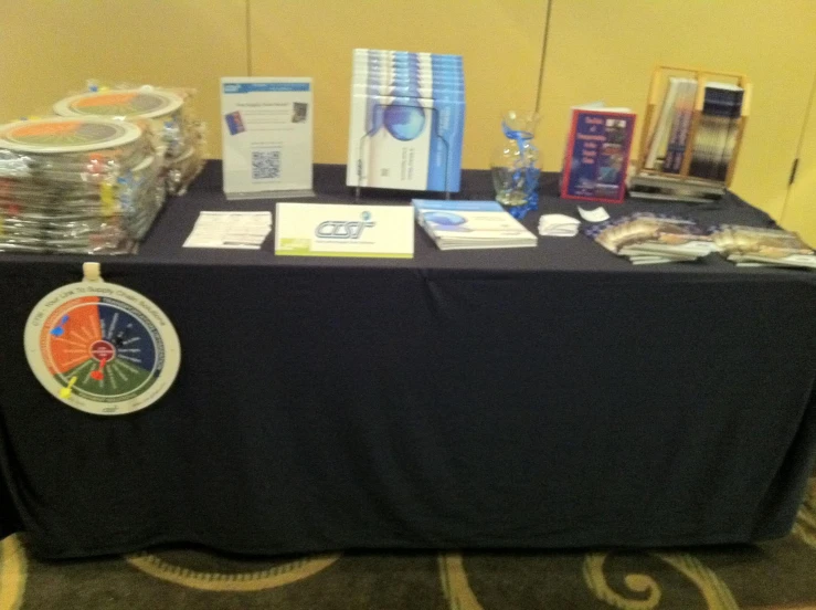 a blue tablecloth covered table holding items that include water and cards