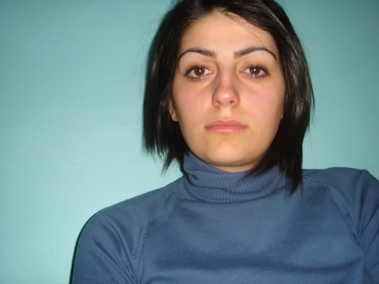 woman with black hair, blue turtle neck shirt, and piercings