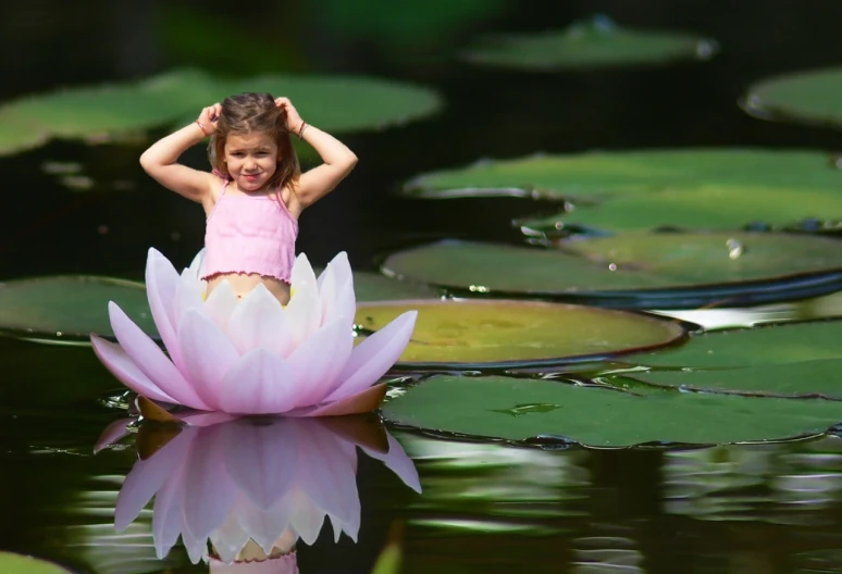 a girl standing on top of a large lily