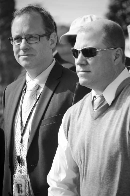 two men standing next to each other wearing sunglasses