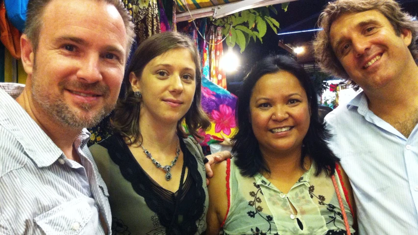 three people posing for the camera in front of some cloth