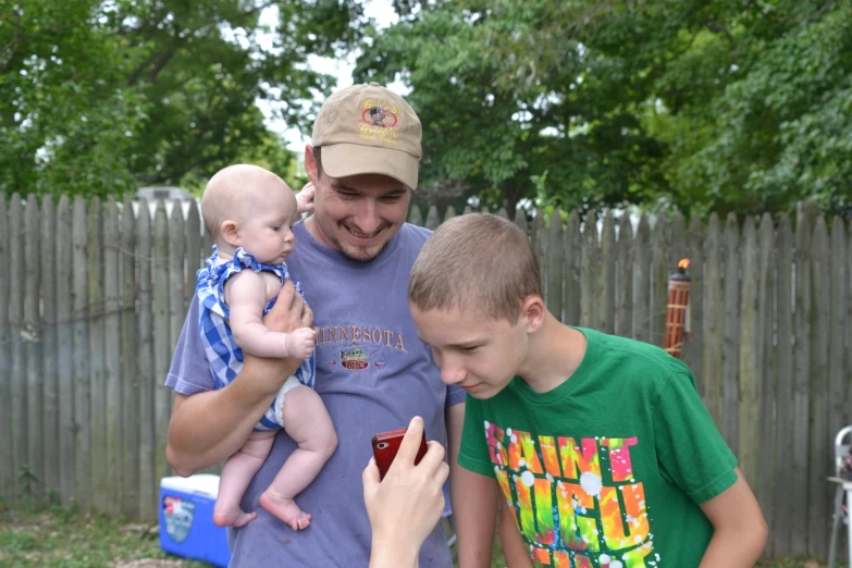 a man with a cap and a baby playing with a cell phone