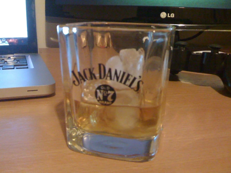 a s glass of jack daniels with the label is on the table beside a laptop