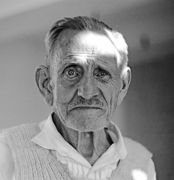 an older man with a mustache wearing a sweater vest