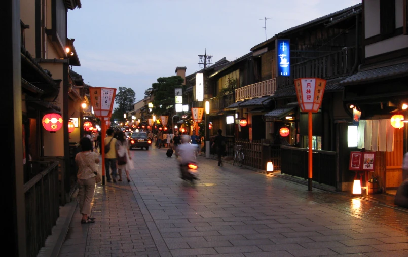 people and lamps line the sidewalks of a town