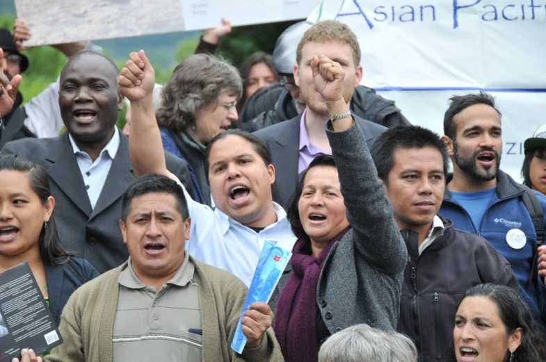 a large group of people standing together holding up signs
