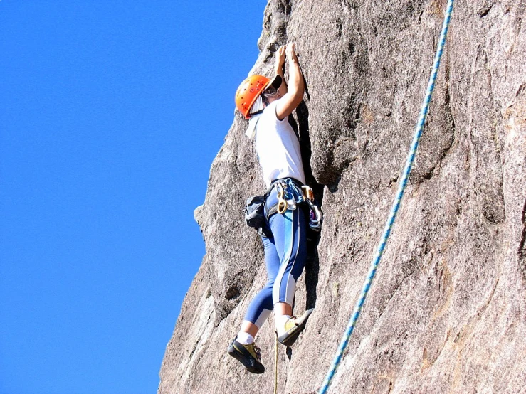someone climbing up a rock formation on a blue sky day