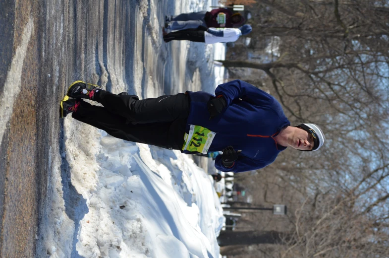 man running down road in snow while woman walking behind