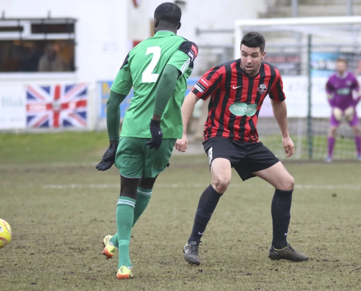 two young men play soccer with the referee looking on