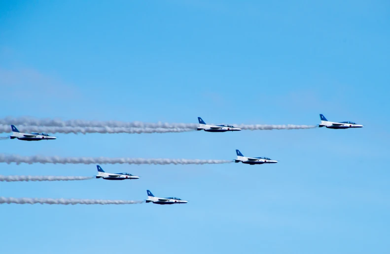 four planes flying in formation in a bright blue sky