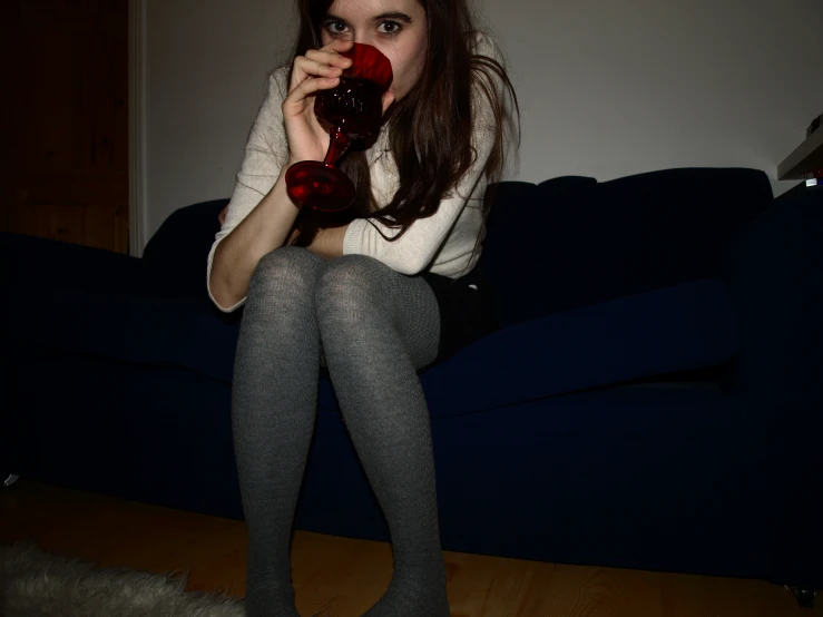 a woman sits on a couch with a red object in her hands