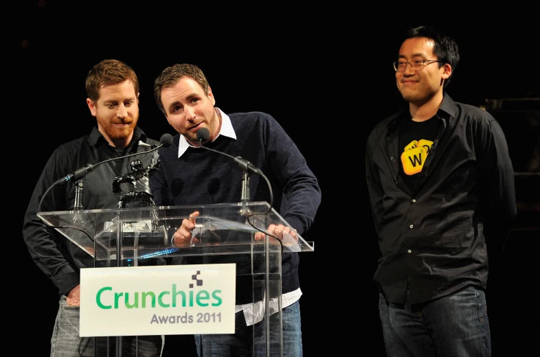 two men standing at a podium and smiling