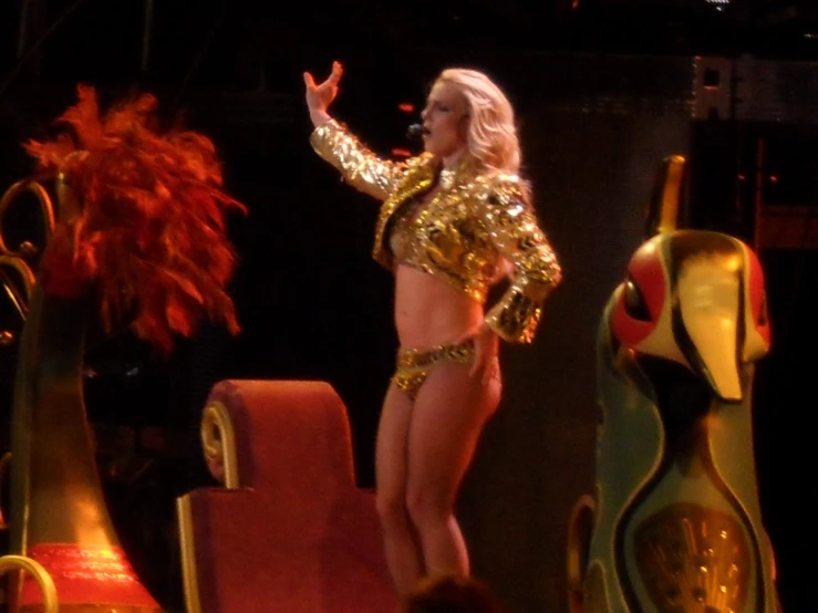 a blond woman wearing gold and standing on stage