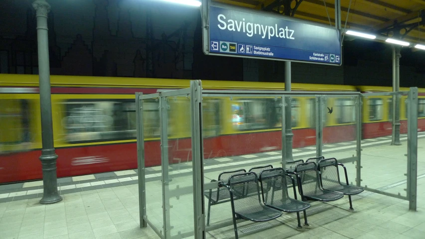 a subway station with three empty benches near the train