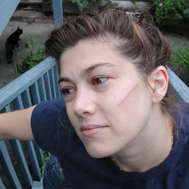 a girl with an arrow drawn on her left cheek and an upside down arm tattoo