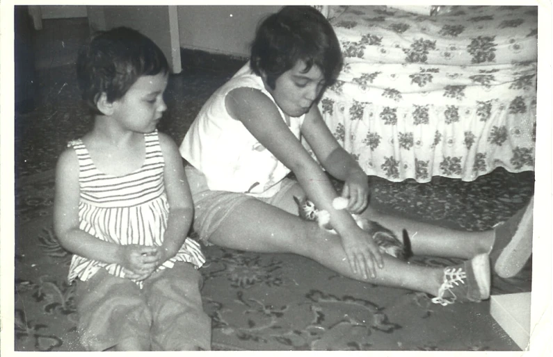 two young children sit on the floor as they look at soing