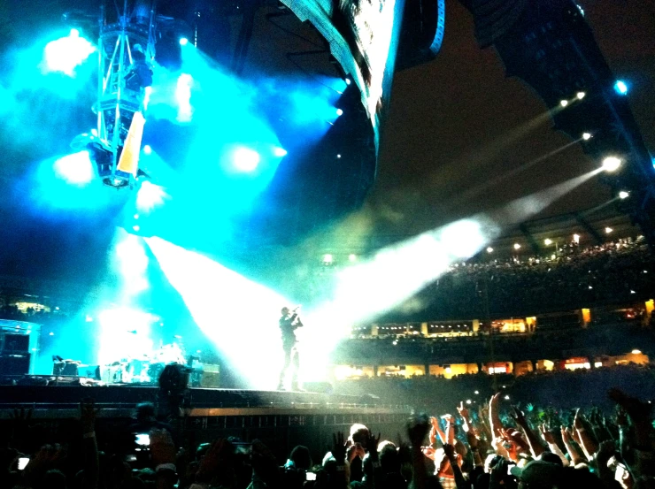 concert lights shine on an outdoor stage as the crowd gets their pictures taken