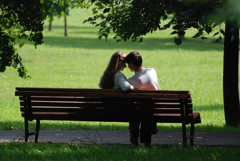 a couple sitting on a park bench kissing