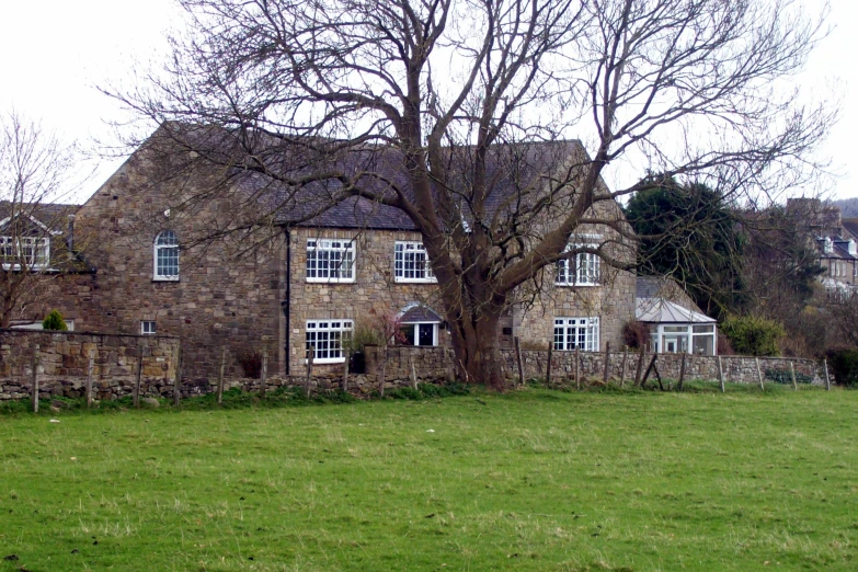 a horse grazing in the grass next to an old house