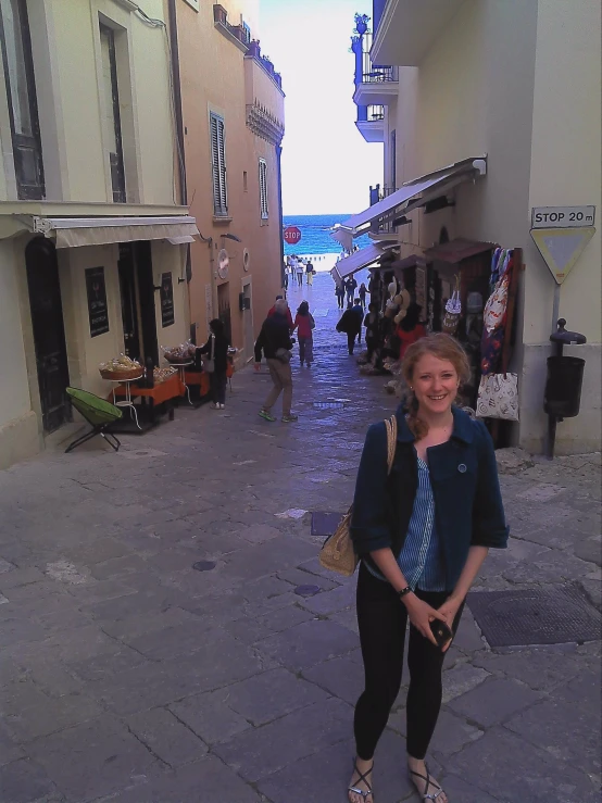 a woman standing in an alley way near several buildings