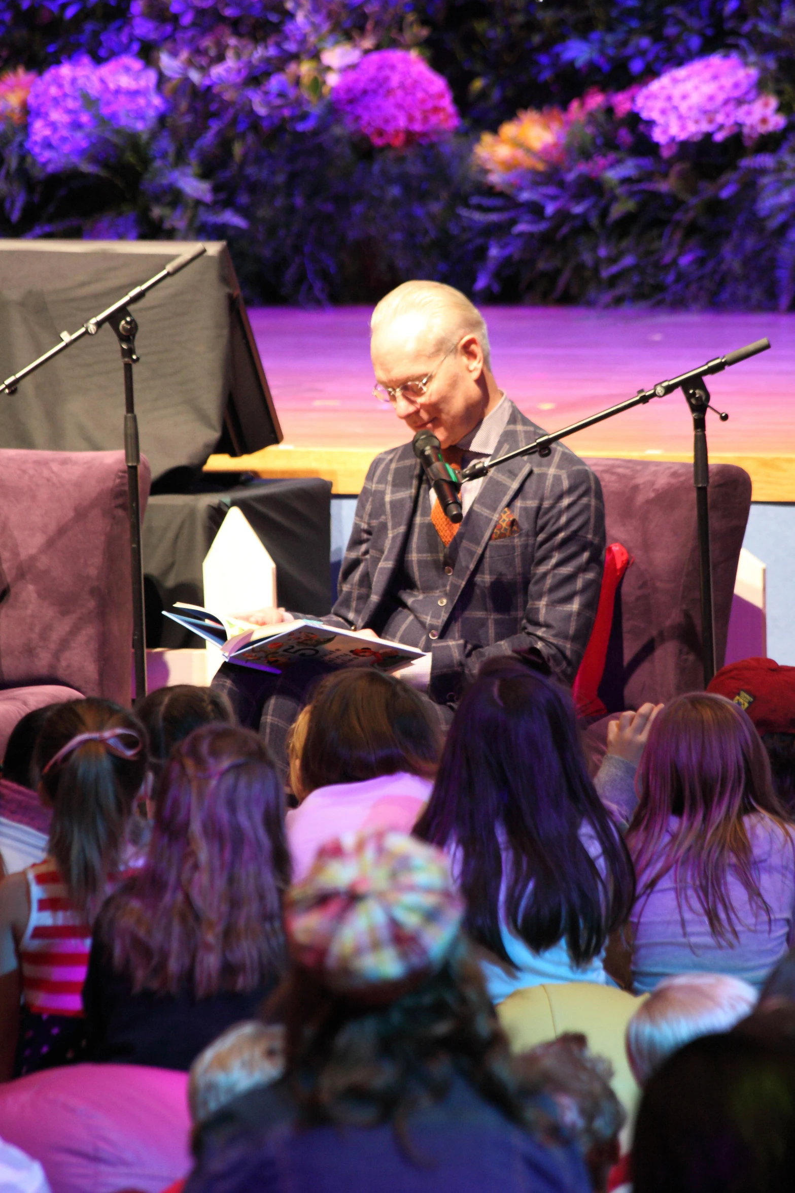 a man is reading a book in front of a crowd