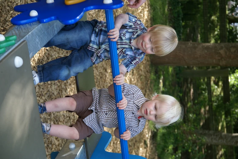 two small boys are playing on the swing set