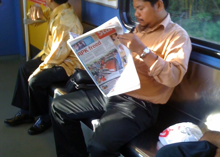 a man sitting on a train reading a paper