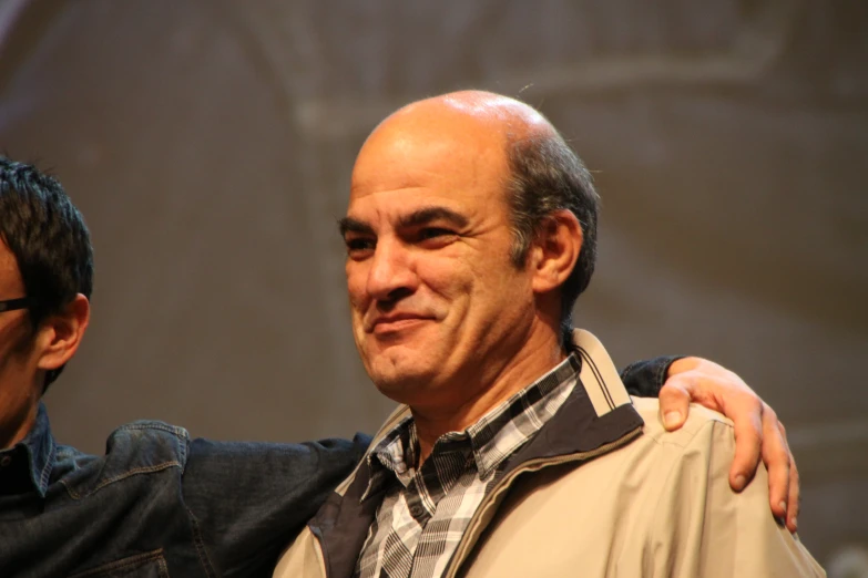 two men stand together, one holding his jacket over his shoulder