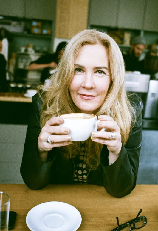 a woman eating some food while drinking a cup of coffee