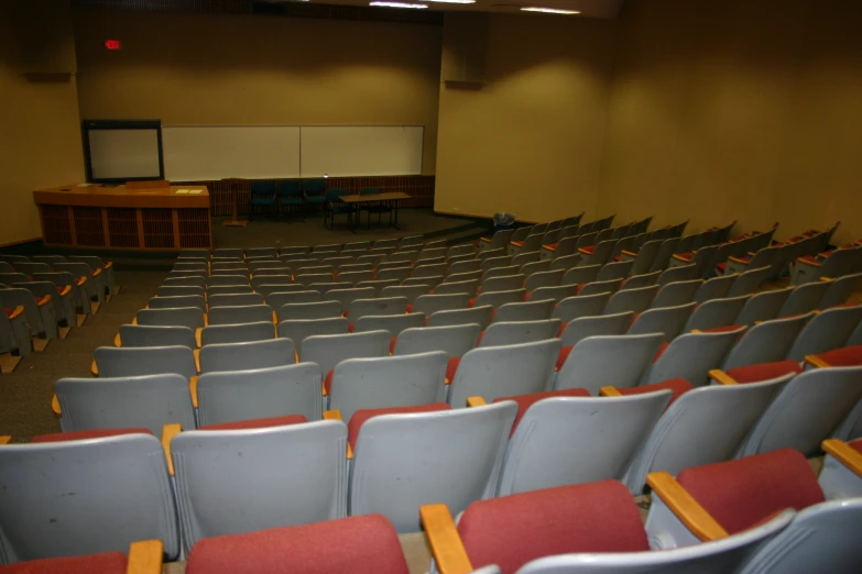 an empty lecture hall is seen from the rear, rows of empty chairs are in front