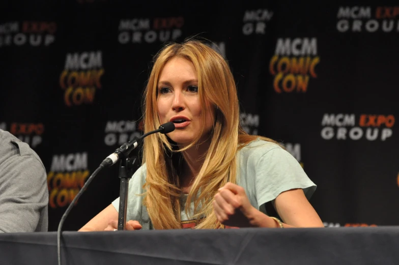 a woman holding a microphone standing in front of a microphone