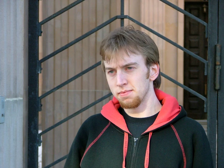 a young man in a black shirt, red and green jacket