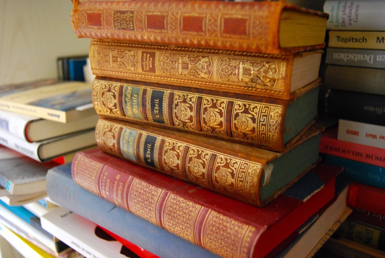 stacks of old books sitting on top of a desk